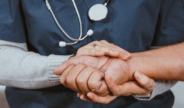 Photo of nurse clutching hand of a patient