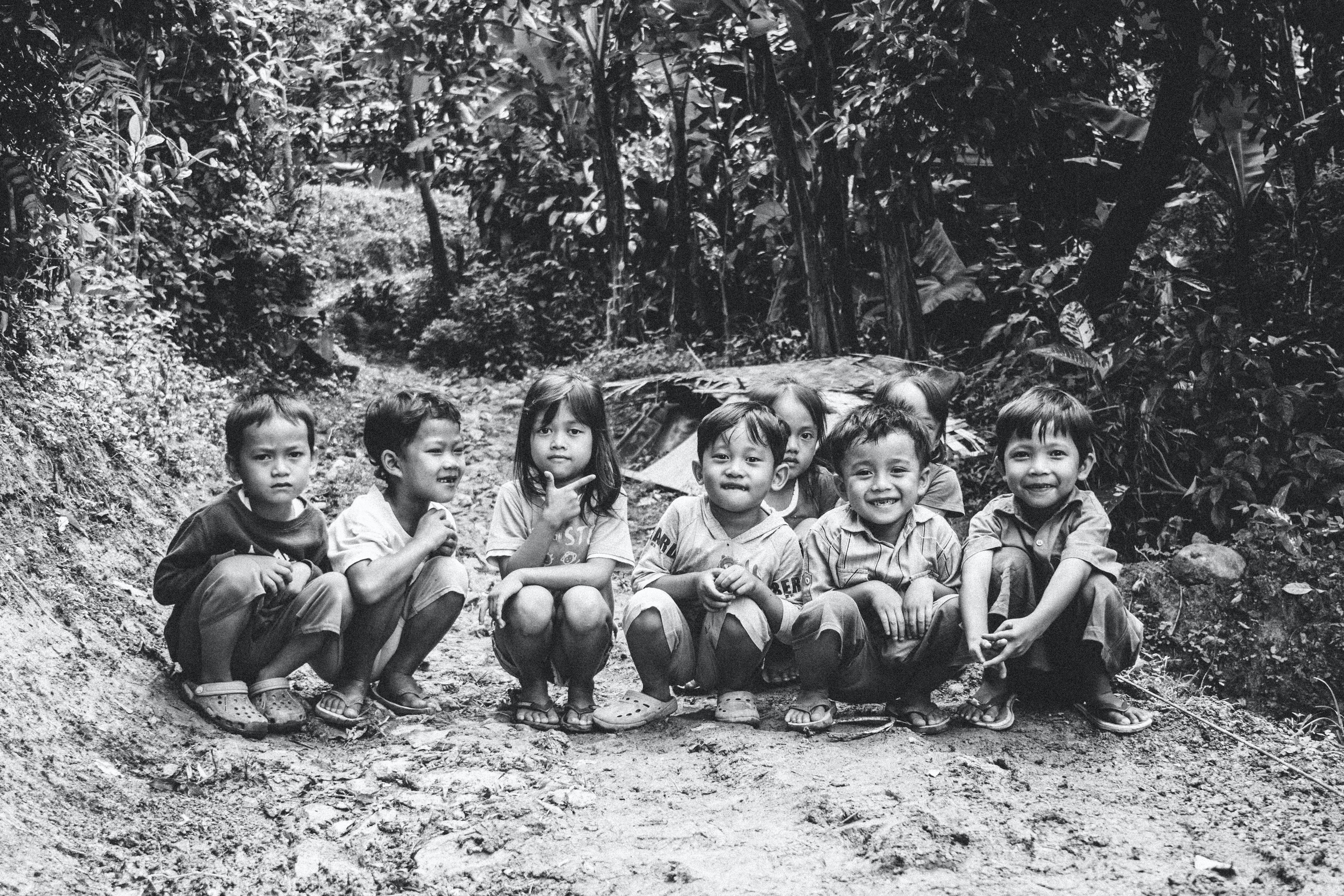 A group of young Asian children sitting on a path outdoors