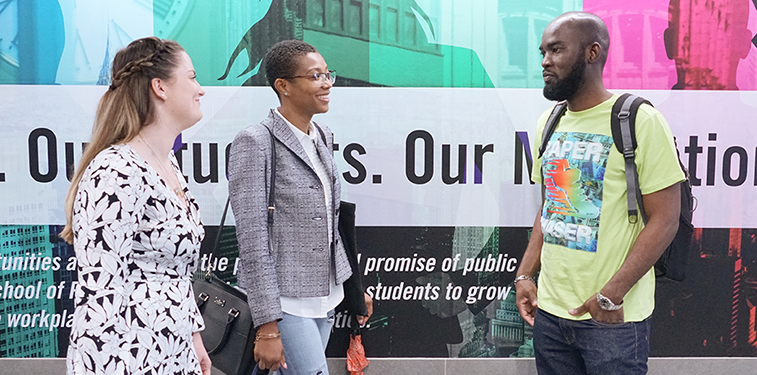 Three students are talking in the CUNY SPS lobby entrance.