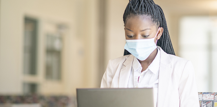 University Student on Campus Wearing Mask and Working on Laptop