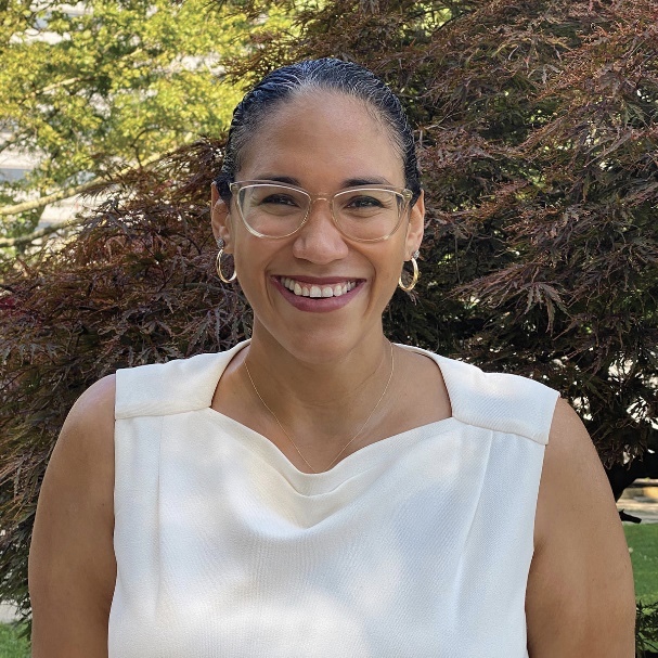 Photo of Dr. Vanessa K. Valdés in a white shirt with trees in the background