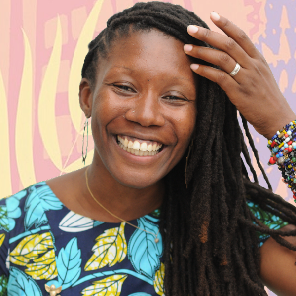 A Black woman with long braided hair smiles at the camera. Her left arm is touching her forehead.