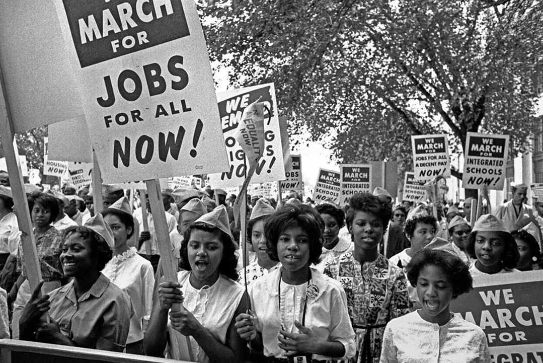 Photo of hundreds of African American women marching in protest with signs about jobs and integrating schools.
