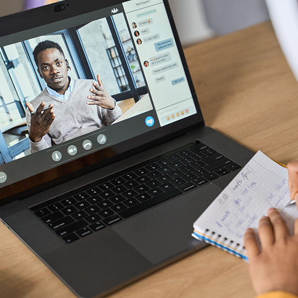 Two African American male students communicating over video chat on laptop