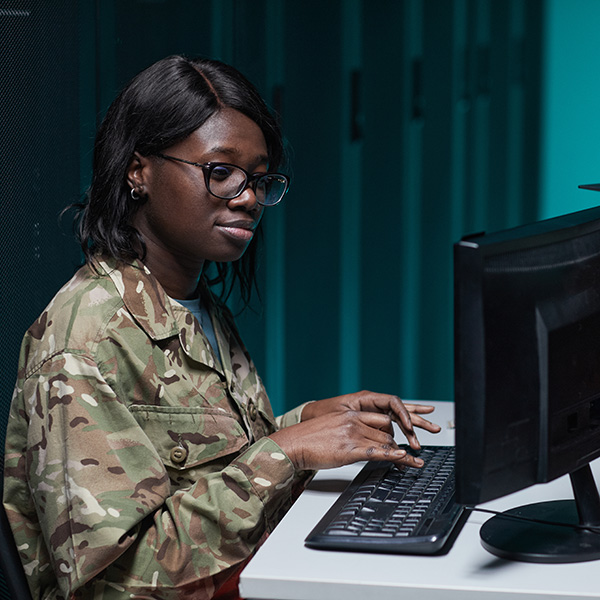 African American military woman using computer in server room