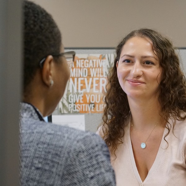 Female African Amrican CUNY SPS student having conversation with academic advisor, back to camera, academic advisor is facing camera