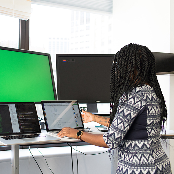 Female IT worker on laptop with two monitors