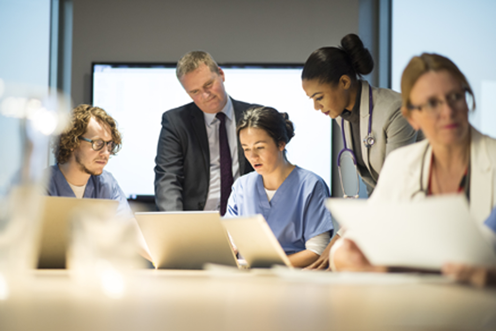 Doctors, nurses, and hospital administrators sitting at table reviewing charts