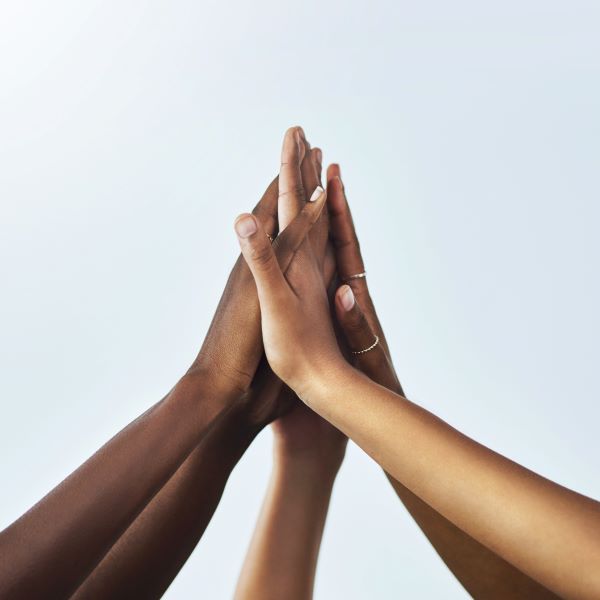 Photo of the hands of five young people clasped together