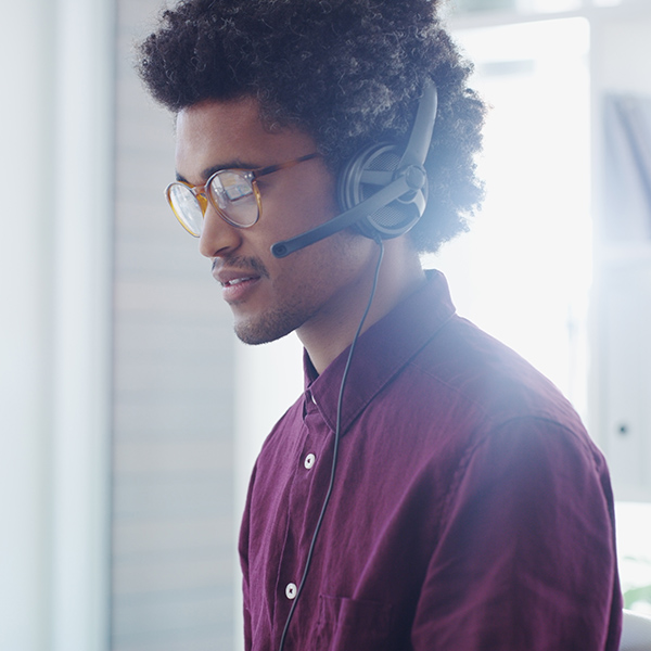 Shot of young man in IT profession using a headset in a modern office