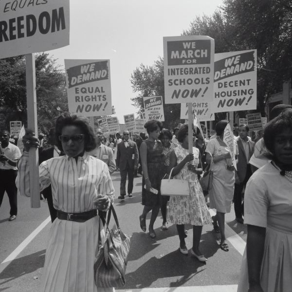 Archival photo of civil rights march on Washington, D.C. in 1963 showing women holding signs to demand equal rights