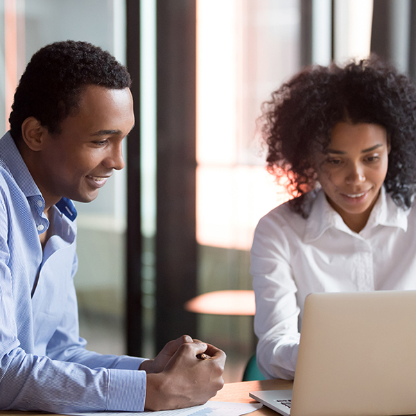 Man and woman smiling while working together on laptop