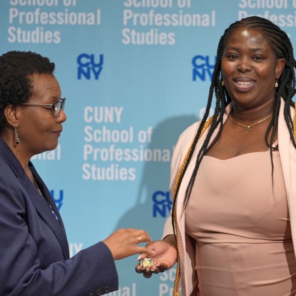 CUNY SPS Nursing staff handing nursing pin to smiling graduate