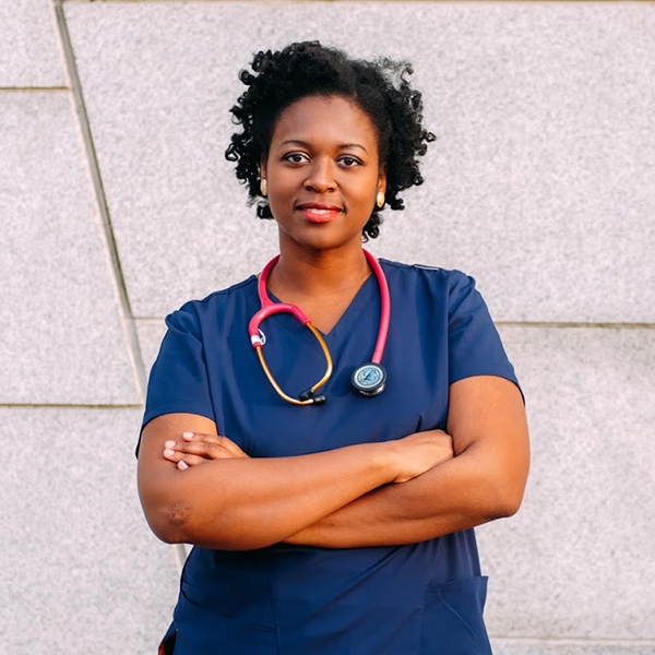 Phara Souffrant, arms crossed, wearing nurse scrubs