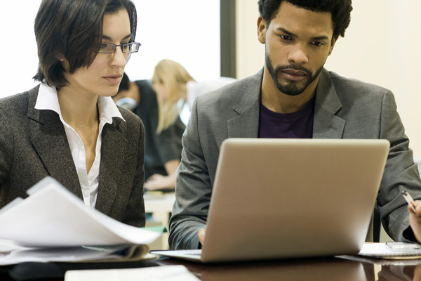 Man and woman professionals reviewing work on laptop