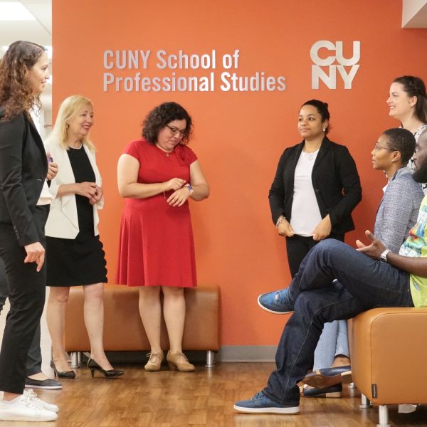 Group of CUNY SPS students chatting in school hallway.