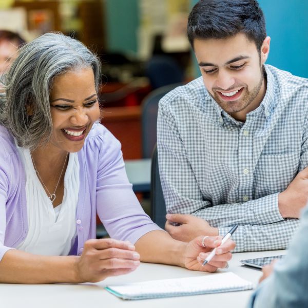 Older female instructor sits down smiling with younger man