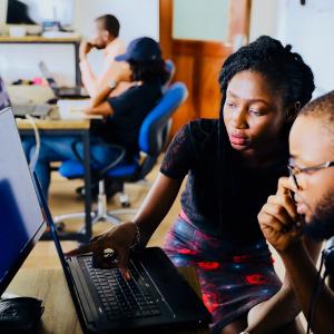 Female and Male African American Students Discussing work on a laptop.