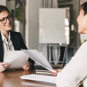 Two women siting at a desk reviewing resumes