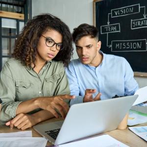 Female and male discussing changes on laptop.