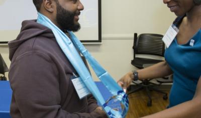 CUNY SPS SEEK (Program Manager) Rianna DeFreece places graduation stole on a SEEK program graduating student. 