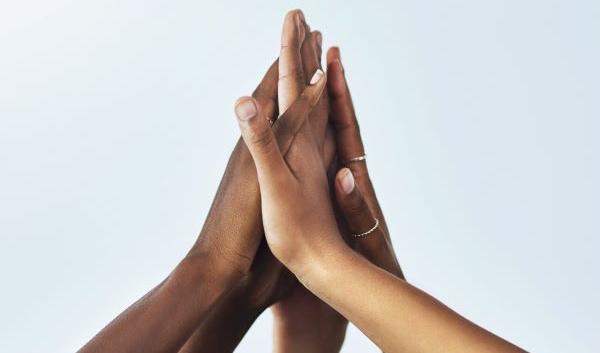 Photo of the hands of five young people clasped together