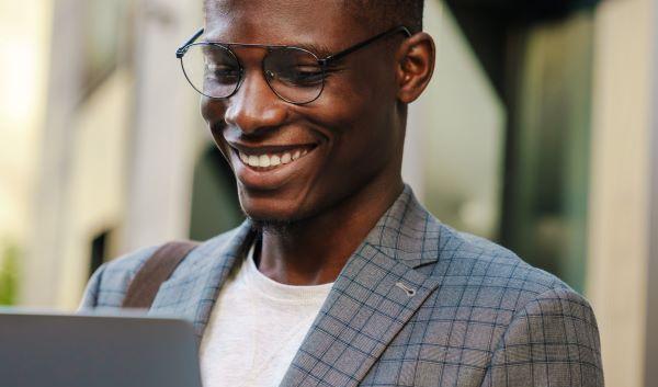 Joyful-african-american-man-smiling-and-using-laptop