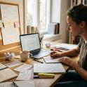 Adult female sitting at desk researching on laptop 