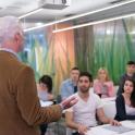 Male professor having a discussion with several male and female student in classroom