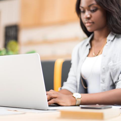 African American Young lady sitting at the table studying on her laptop