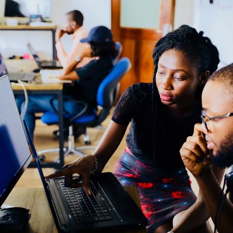 Adult African American female assisting adult African American male on computer at library.