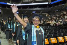 Woman smiling and waving at CUNY SPS commencement