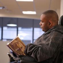 Disability studies student at CUNY SPS reading book in classroom