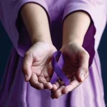 Hands holding purple ribbon in honor of Domestic Violence Awareness Month