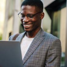 Joyful-african-american-man-smiling-and-using-laptop