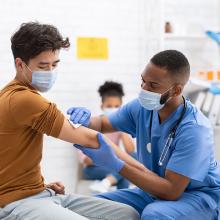 Male African American nurse vaccinating patient for COVID-19
