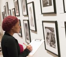 Woman standing in front of museum art writing notes in a notebook