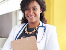 Nurse in white coat and stethoscope holding a clipboard smiling at the camera.