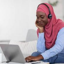 Smiling Black Muslim Woman Watching Webinar on Laptop