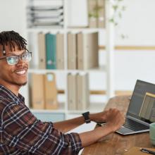 smiling-african-american-man-writing-programming-at-desk