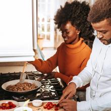 Young African American couple cooking dinner in kitchen