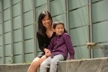 Middle aged Asian woman sitting outside with her young son.